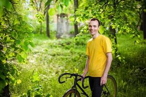 A young Man stopped to rest With his Bicycle in a public Park. photo