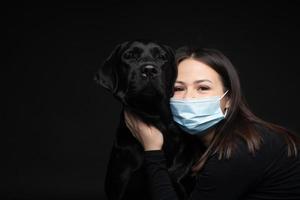 Portrait of a Labrador Retriever dog in a protective medical mask with a female owner. photo