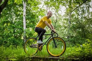 un joven se detuvo a descansar con su bicicleta en un parque público. foto