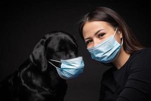 retrato de un perro labrador retriever con una máscara médica protectora con una dueña. foto