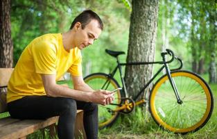 A young man sitting on a bench in a public Park communicates via mobile communication. photo