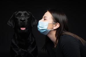 Portrait of a Labrador Retriever dog in a protective medical mask with a female owner. photo