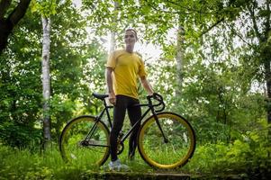 un joven se detuvo a descansar con su bicicleta en un parque público. foto