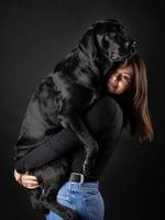 A girl holds a Labrador Retriever dog in her arms. photo