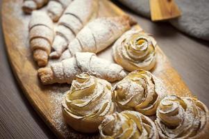 Close up of delicious croissants and pastries with apples, on a wooden Board in a cafe photo