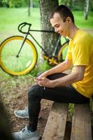 A young man sitting on a bench in a public Park communicates via mobile communication. photo