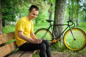 A young man sitting on a bench in a public Park communicates via mobile communication. photo