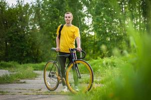 un joven se detuvo a descansar con su bicicleta en un parque público. foto