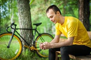 A young man sitting on a bench in a public Park communicates via mobile communication. photo