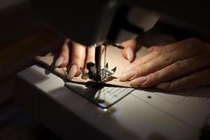 The woman is sewing with sewing machine. Sewing is one of the oldest of the textile arts. photo