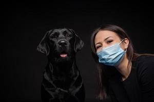 Portrait of a Labrador Retriever dog in a protective medical mask with a female owner. photo