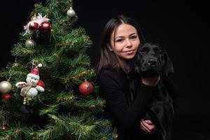 retrato de un perro labrador con su dueño, cerca del árbol verde de año nuevo. foto