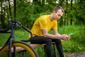 A young man sitting on a bench in a public Park communicates via mobile communication. photo