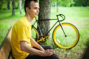 A young man sitting on a bench in a public Park communicates via mobile communication. photo