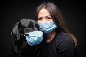 Portrait of a Labrador Retriever dog in a protective medical mask with a female owner. photo