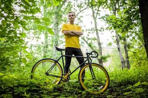 un joven se detuvo a descansar con su bicicleta en un parque público. foto