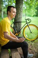 A young man sitting on a bench in a public Park communicates via mobile communication. photo