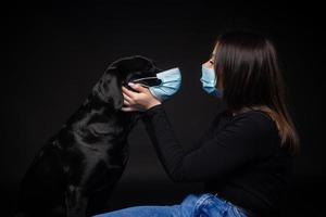 Portrait of a Labrador Retriever dog in a protective medical mask with a female owner. photo