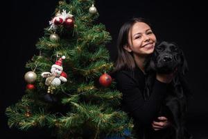 retrato de un perro labrador con su dueño, cerca del árbol verde de año nuevo. foto