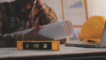 Two colleagues discussing data working and tablet, laptop with on on architectural project at construction site at desk in office video