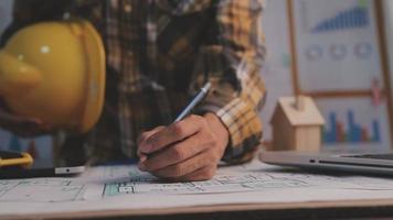 Dos colegas discutiendo el trabajo de datos y una tableta, un portátil con un proyecto arquitectónico en el sitio de construcción en un escritorio en la oficina video