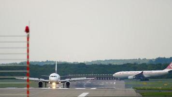 DUSSELDORF, GERMANY JULY 22, 2017 - AlMasria Universal Airlines Airbus 320 SU TCE taxiing after landing, and Turkish Airlines Airbus A330 in retro livery turn runway. Dusseldorf Airport, Germany video