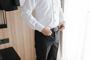 Close up preparation pose of a man holding his black belt and white shirt.