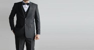 detalle medio cuerpo de cerca un traje negro de hombre con chaleco interior con corbata de moño y camisa blanca. foto