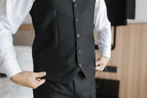 Close up preparation pose of a man fixing and holding the bottom of his black tuxedo and white shirt. photo