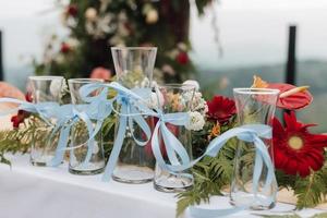 hermosa boda al aire libre con tema rústico o cena romántica, configuración de altar blanco, jarrones de ceremonia de arena de boda con vidrio alineado con decoración de flores naturales. foto