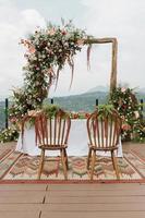 Beautiful rustic theme outdoor wedding white altar setup, with natural flower decoration and mountain background. photo