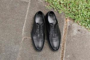 A pair of formal black gentlemen shoes laying on the ground, with negative space good for concept print. photo