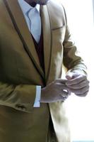 cierre la pose de preparación de un hombre que se fija y un hombre que sostiene los botones en el traje de mangas. foto