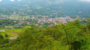 the view of the cloudy sky, trees, mountains and houses was photographed from above the hill photo