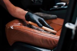 Taking care about brown colored seats. Modern black automobile get cleaned by woman inside of car wash station photo