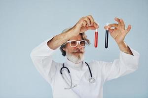 Doctor holds test tubes. Senior stylish modern man with grey hair and beard indoors photo