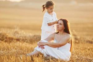 Happy mother with her little daughter spending time together outdoors on the field photo