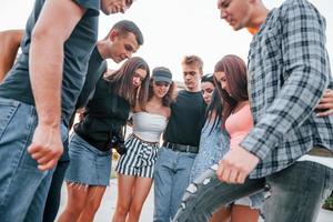 hablando y riendo. grupo de jóvenes amigos alegres divirtiéndose juntos. fiesta al aire libre foto