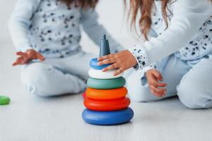 Playing with toy. Two cute little girls indoors at home together. Children having fun photo