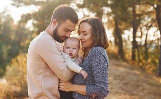 Happy family of mother, family and little baby rests outdoors. Beautiful sunny autumn nature photo