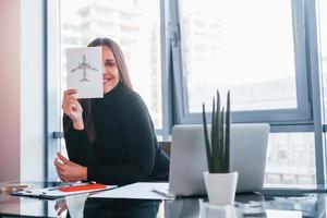 With laptop on table. Woman in black formal clothes is indoors in the modern office photo