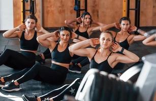 Busy by doing exercises. Group of young sportive people have crossfit day indoors in gym photo