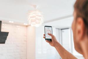 Rear view of adult man that is indoors controlling smart home technology photo