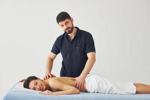 Young woman is lying down when man doing massage of her body at spa photo