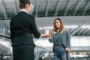 Vaccination certificate in the phone. Young female tourist is in the airport at daytime photo