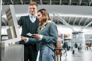 Male worker helping woman. Young female tourist is in the airport at daytime photo