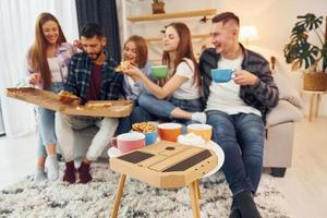 comiendo comida y bebiendo té. grupo de amigos tienen una fiesta en el interior juntos foto