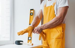 Handyman in yellow uniform preparing for work indoors. House renovation conception photo