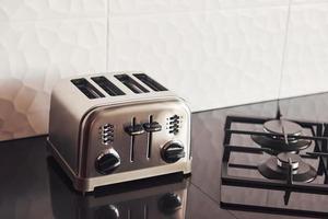 Close up view of silver colored toaster that standing on gas stove indoors in kitchen photo