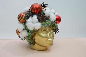 Festive Christmas accessories - red balls, fir cones and cotton on a stylized golden female head. Interior Christmas composition. photo